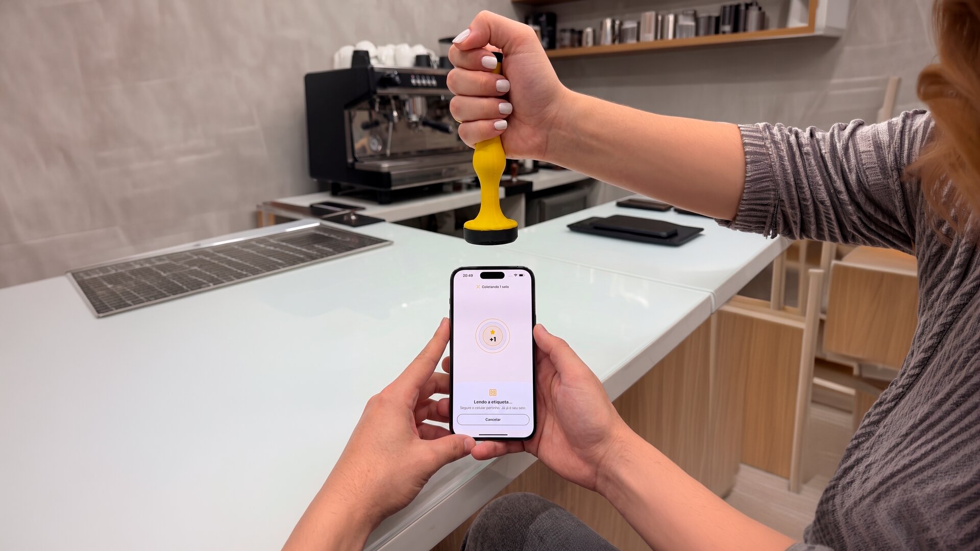 Barista aproxima o carimbo digital do celular do cliente, que recebe um selo no app do Freguês